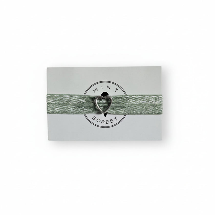 Green elastic bracelet with silver heart charm on Mint Sorbet packaging card