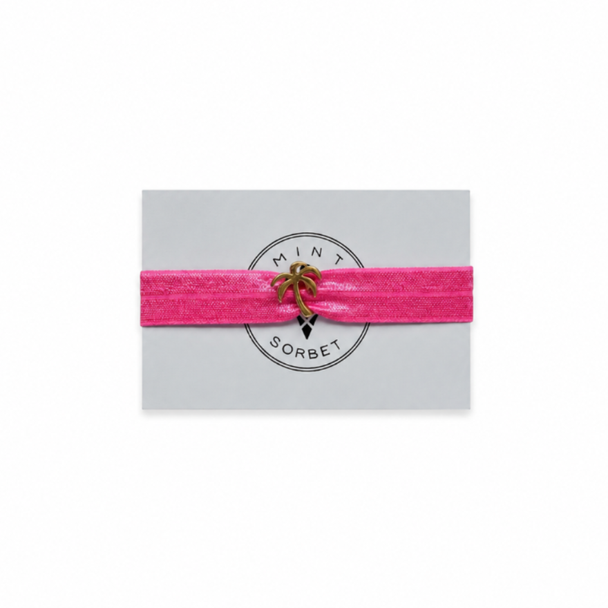 Pink elastic bracelet with gold palm tree charm on Mint Sorbet packaging card