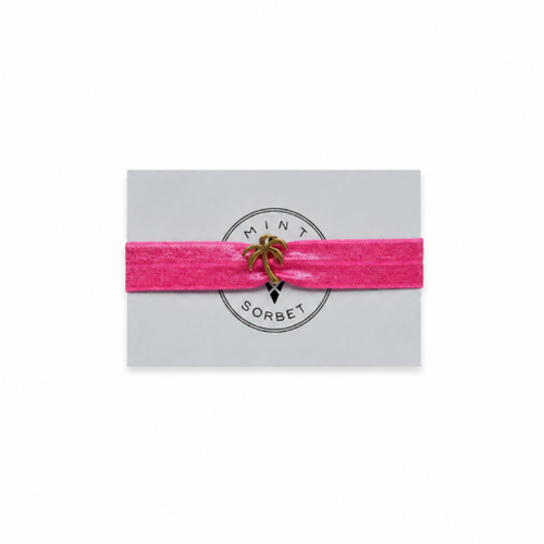 Pink elastic bracelet with gold palm tree charm on Mint Sorbet packaging card