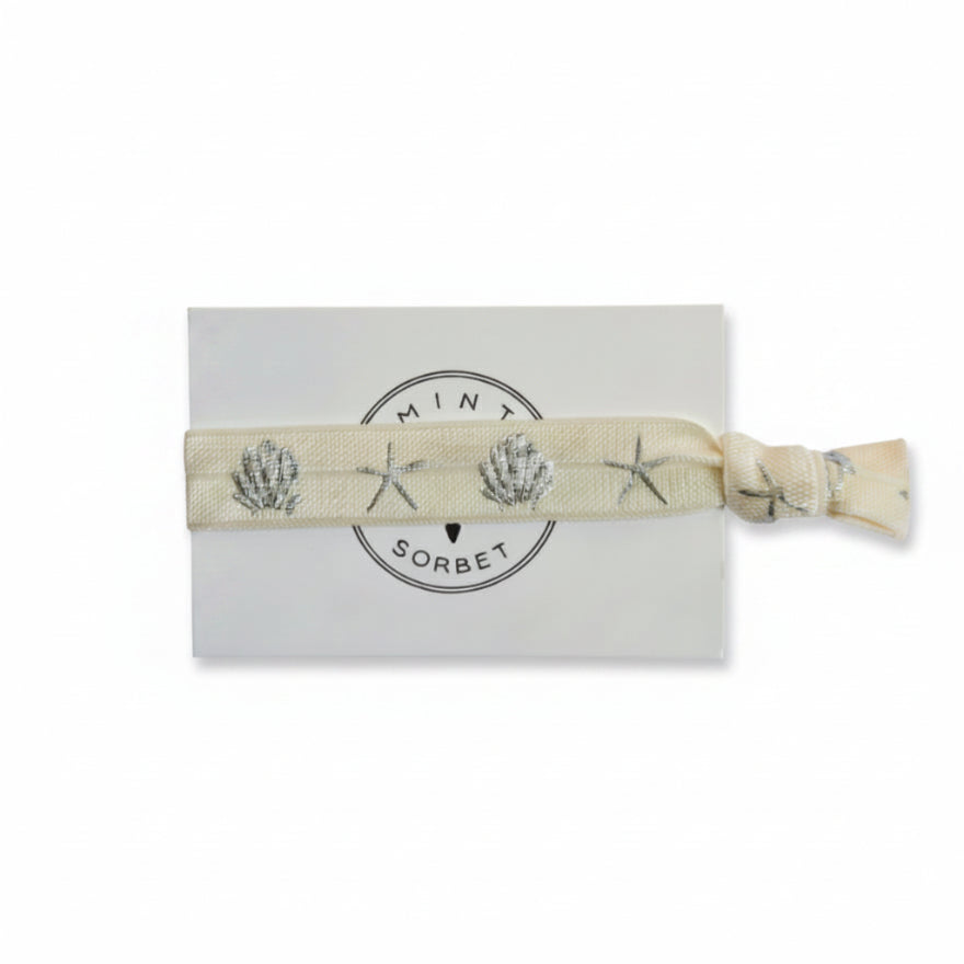Beige elastic bracelet with silver seashell and starfish print on Mint Sorbet packaging card
