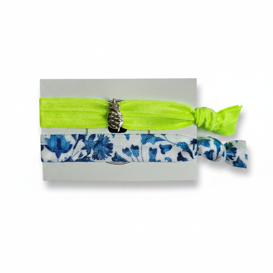 Neon yellow elastic hair tie set with blue floral band and silver pineapple charm on Mint Sorbet packaging card