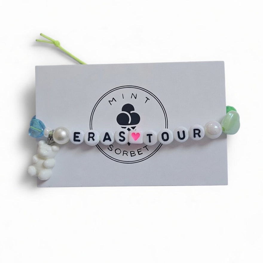 Handmade Eras Tour friendship bracelet with letter beads, heart bead and teddy bear charm on Mint Sorbet packaging card