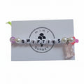 Handmade Swifties friendship bracelet with letter beads, pink glass beads and gummy bear charm on Mint Sorbet packaging card