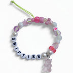 Handmade Swifties friendship bracelet with letter beads, pink glass beads and gummy bear charm – product view
