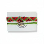 Red and green hand-knotted cotton friendship bracelet set with chevron pattern and green cord bracelet with silver cowrie shell charm on Mint Sorbet packaging card