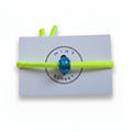 Neon yellow elastic bracelet with teal blue Murano glass bead on Mint Sorbet packaging card