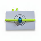 Neon yellow elastic bracelet with teal blue Murano glass bead on Mint Sorbet packaging card