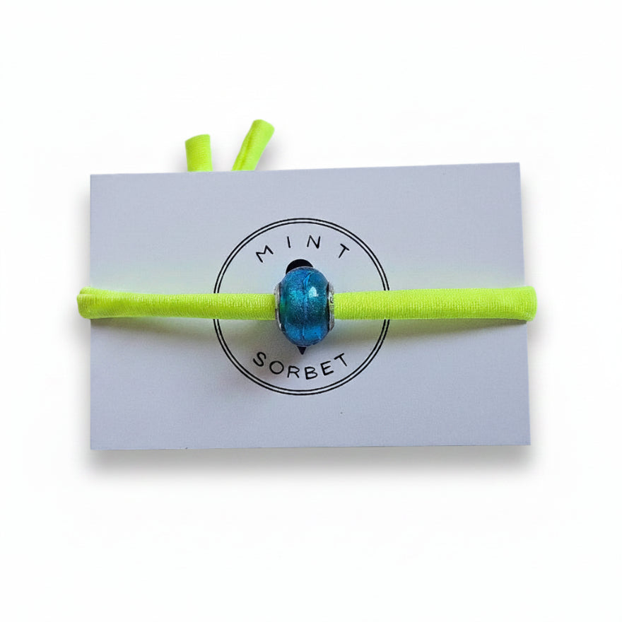 Neon yellow elastic bracelet with teal blue Murano glass bead on Mint Sorbet packaging card