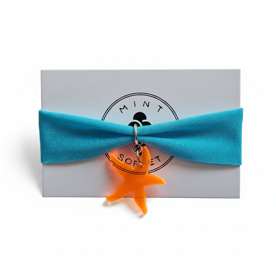 Turquoise nylon elastic bracelet with orange acrylic starfish pendant on Mint Sorbet packaging card