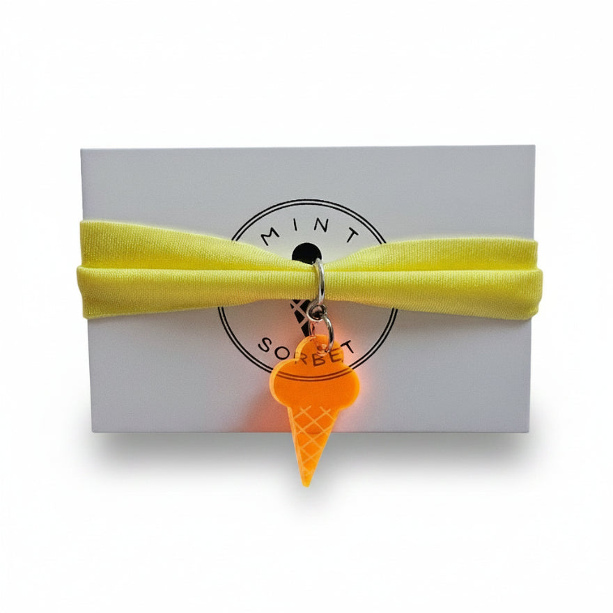 Yellow nylon elastic bracelet with orange acrylic ice cream cone pendant on Mint Sorbet packaging card