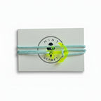 Light blue paracord bracelet with neon yellow acrylic anchor pendant on Mint Sorbet packaging card